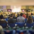 A lot of young people in a big hall listening to a speaker